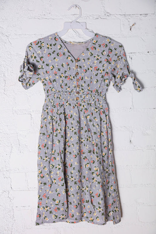 Floral dress on a hanger against a white brick wall
